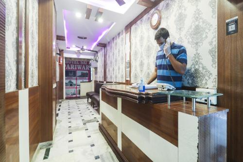 a man talking on a phone at a counter in a restaurant at Hotel O Sai Pariwar in Vidya Nagar
