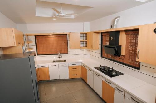 a large kitchen with white cabinets and a sink at Nigara Residency in Vandanmedu