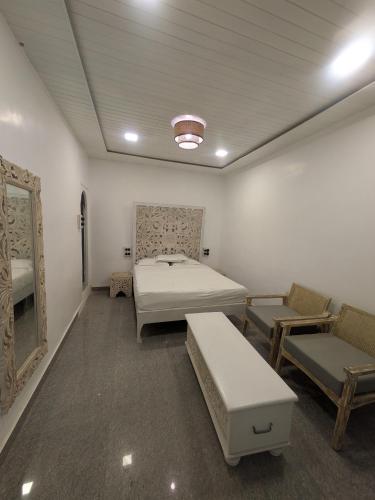 a room with a bed and a couch and chairs at Nomada in Mount Ābu