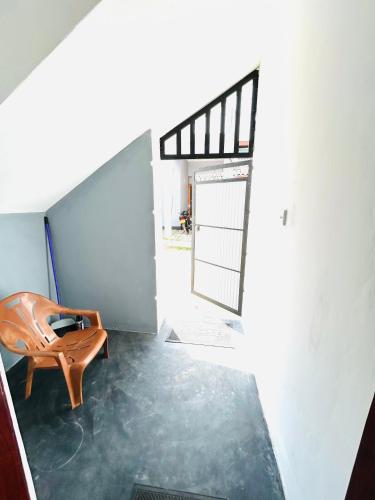 a room with a wooden chair and a door at Just Inn in Puttalam