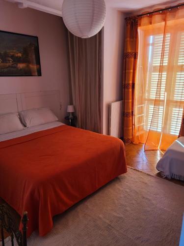 a bedroom with a bed with an orange blanket at B&B Ma Maison in Govone