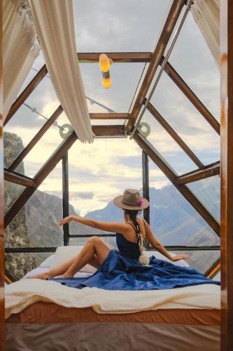 a woman sitting on a bed in a tent at Vertical Sky Suites in Ollantaytambo
