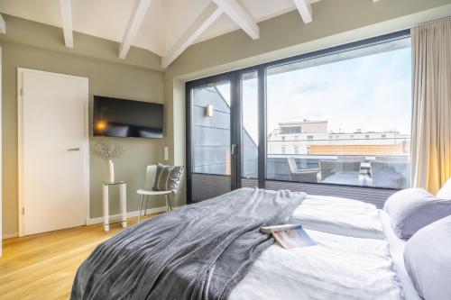 a bedroom with a bed and a large window at InselLoft Wohnung 6 in Borkum