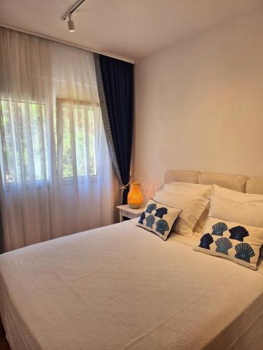 a bedroom with a large white bed and a window at Sea Colours Apartment Budva in Budva