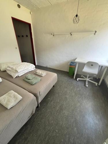 a room with two beds and a desk and a computer at Campus Djursland in Grenå