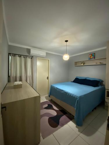 a bedroom with a blue bed and a desk at Apartamento á 5 minutos do centro in Garanhuns