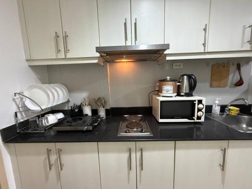 a kitchen with a counter top with a microwave at Sea Residences MOA Pasay City - Rose Staycation in Manila