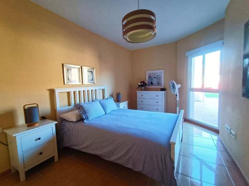 a bedroom with a bed with blue sheets and a window at Miramar 8 - San Sebastin de La Gomera in San Sebastián de la Gomera