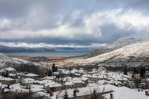 a town covered in snow with a lake and mountains at Panorama Prespes in Agios Germanos
