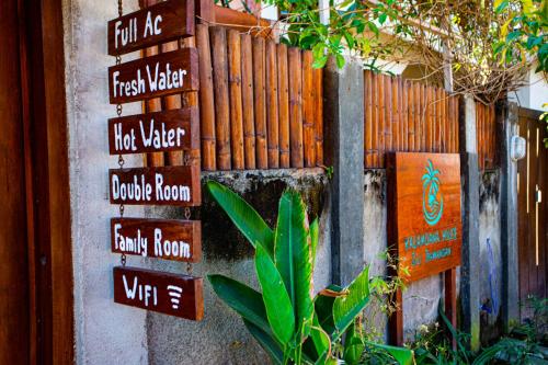 a bunch of signs on the side of a fence at Kalamoana House in Gili Trawangan