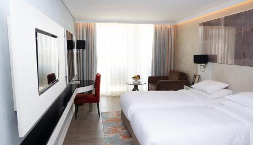 a hotel room with a white bed and a chair at Rixos Premium Dubrovnik in Dubrovnik