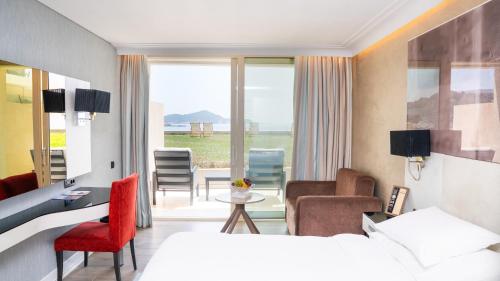 a hotel room with a bed and a desk and chairs at Rixos Premium Dubrovnik in Dubrovnik