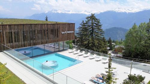 a swimming pool with chairs and mountains in the background at Holidays Groupes Anzère in Anzère