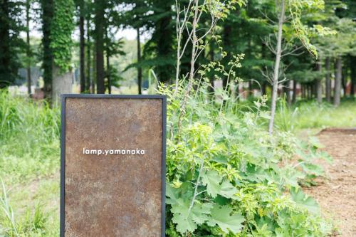 a sign in a park next to a bush at lamp yamanaka-山中湖 河口湖 プライベートヴィラ-132平米-最大10名-BBQ無料-乳幼児可-長期滞在設備充実-山中湖車5分-河口湖車20分 in Yamanakako