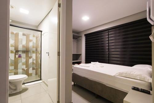 a bedroom with a large bed and a bathroom at Lou Suítes - Suíte 01 - Sonho e Descanso in Guarapuava