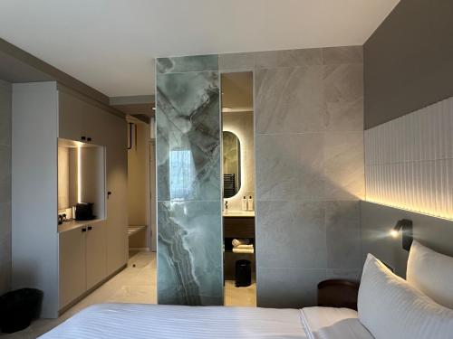 a hotel room with a bed and a marble wall at James Vignoble Hôtel, Eguisheim in Eguisheim