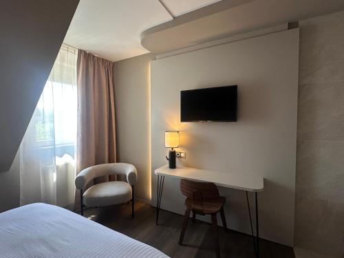 a hotel room with a desk and a tv on the wall at James Vignoble Hôtel, Eguisheim in Eguisheim