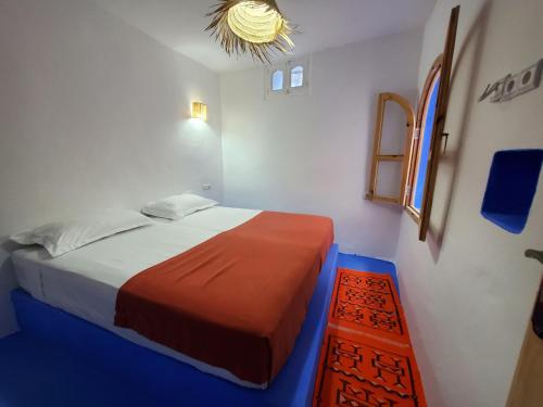 Habitación pequeña con cama y lámpara de araña. en Casa Autiui, en Chefchaouen