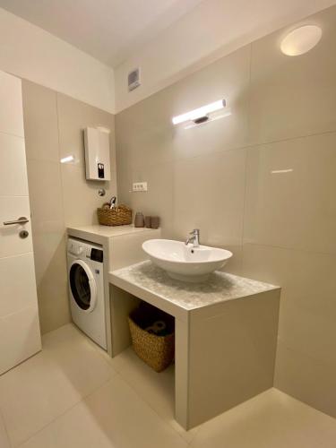 a bathroom with a sink and a washing machine at Apartmani PERLA 55 in Poreč