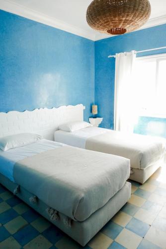 two beds in a bedroom with blue walls at Blue Kaouki Boutique Hotel in Sidi Kaouki