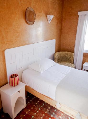 a bedroom with a white bed and a chair at Blue Kaouki Boutique Hotel in Sidi Kaouki