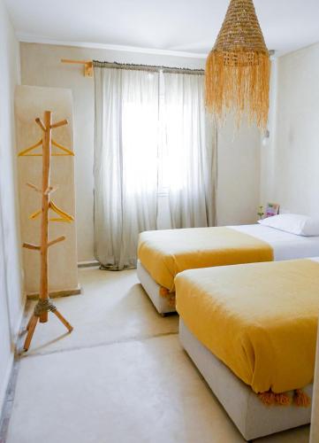 two beds in a room with yellow sheets at Blue Kaouki Boutique Hotel in Sidi Kaouki