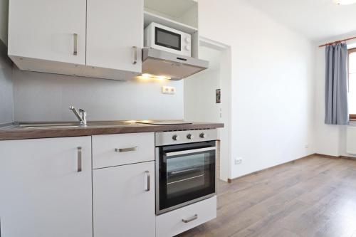 a kitchen with white cabinets and a microwave at Penzion Vintrovna in Popůvky