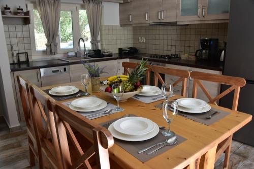 a wooden table with chairs and plates and wine glasses at Geropalas Spacious Garden House in Vlachopoulátika
