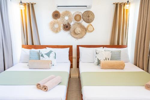 two beds in a room with hats on the wall at Casa Maria at Bigang Munti in San Juan