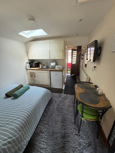 a room with a bed and a table and a kitchen at 16 BENTLEY ROAD - Uttoxeter, ENTIRE HOLIDAY HOME, COSY ACCOMMODATION in Uttoxeter