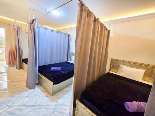 two beds in a room with blue curtains at Afnan Cairo Airport in Cairo