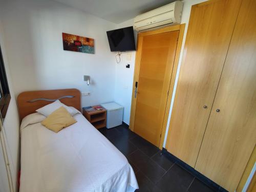 a small bedroom with a bed and a wooden closet at Hostal Manel in Pineda de Mar