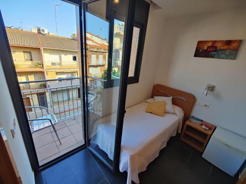 a small bedroom with a bed and a balcony at Hostal Manel in Pineda de Mar