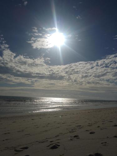 a sun shining on a beach with footprints in the sand at Casas Bennu Preá in Prea