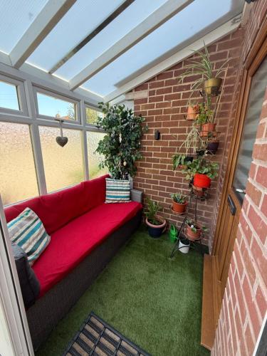 a small patio with a red couch in a brick wall at 16 BENTLEY ROAD - Uttoxeter, ENTIRE HOLIDAY HOME, COSY ACCOMMODATION in Uttoxeter
