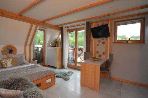 a bedroom with a bed and a desk and a television at Lux Houses w DOMKU tylko DWA APARTAMENTYz jacuzzi zewnętrznym in Groń