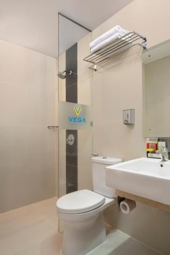 a white bathroom with a toilet and a sink at Vega Hotel Gading Serpong in Serpong