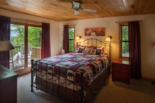 a bedroom with a bed with a wooden ceiling and windows at Get-away Cabin Hot Tub Sunsetmtn Views,asheville in Swiss