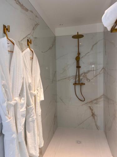 a bathroom with white robes hanging in a shower at Le Domaine de la Vallée in Vernon