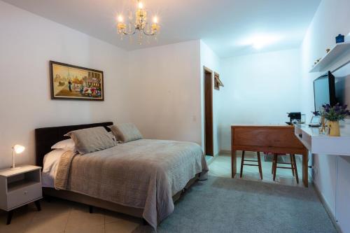 a bedroom with a bed and a desk and a television at Apartamento Le Quatre Avenida in Monte Verde