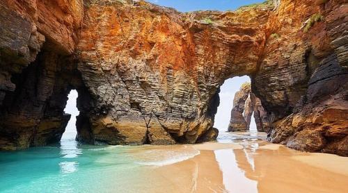 an archway in a rocky cliff next to a beach at El Rincón Del Silencio in Moucide