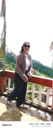 a woman standing next to a fence at Mane Dara homestay in Darjeeling
