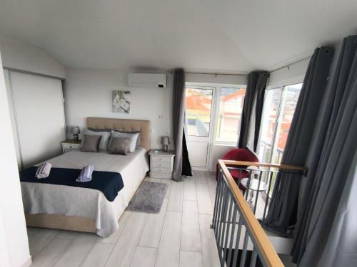 Un dormitorio con una cama y un balcón con ventanas. en Tiny House, en Funchal