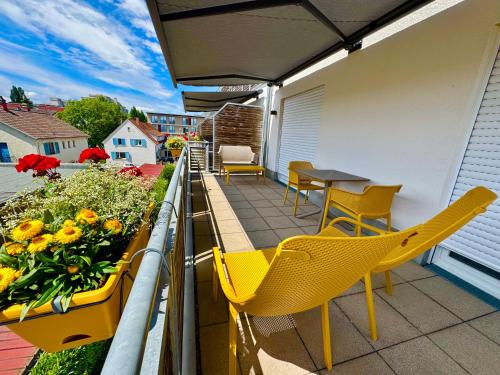 a balcony with yellow chairs and a table and flowers at Boardinghouse HOME - adults only - in Konstanz
