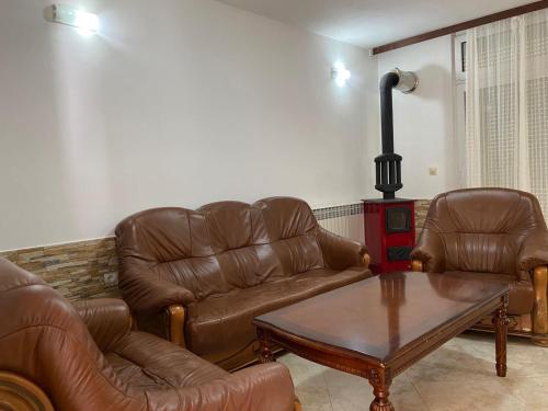 a living room with brown leather furniture and a table at Villa Rezevici in Katun