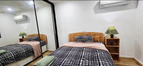 two twin beds in a room with a mirror at Affordable & cosy, close to train station, CBD & Airport in Perth