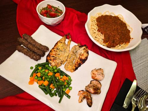 a plate of food with meat and vegetables on a table at Afnan Cairo Airport in Cairo