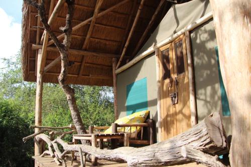 a porch of a house with chairs and a tree at Leopard Rest Camp in Mbarara