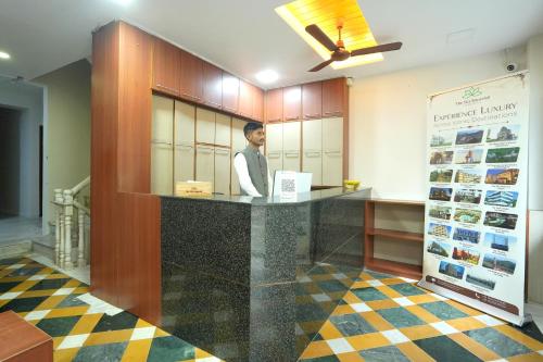 a man standing at a counter in a room at The Sky Comfort Hotel Shreenath - 10 Meters from Shreenathji Temple in Nāthdwāra