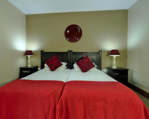a large red bed with two red pillows on it at Chillifields Guesthouse in Hillcrest